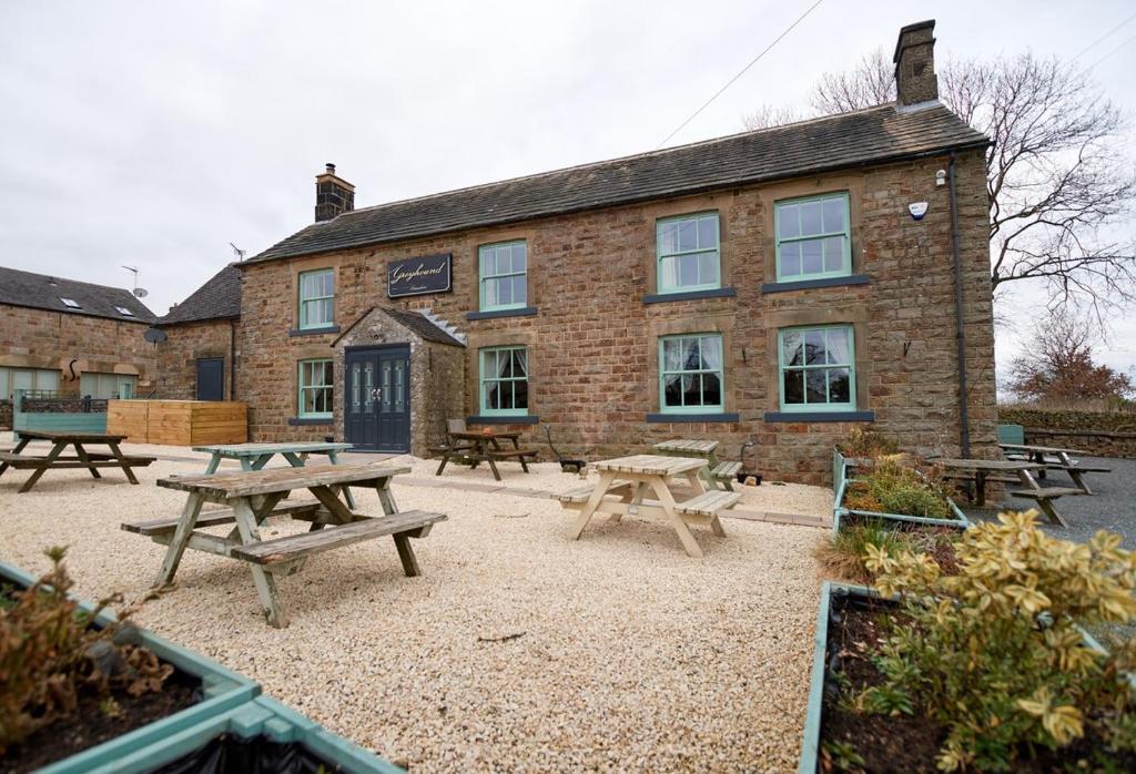 a building with picnic tables in front of it at Peak District, The Greyhound Inn, Warslow circa 1750 in Warslow