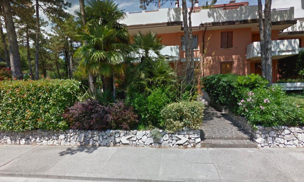 ein Haus mit einer Palme und einer Steinmauer in der Unterkunft BA - Maestrale- in Lignano Sabbiadoro