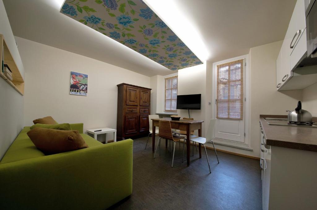 アオスタにあるアパートメント　クール　ド　ヴィルのリビングルーム(緑のソファ付)、キッチンが備わります。