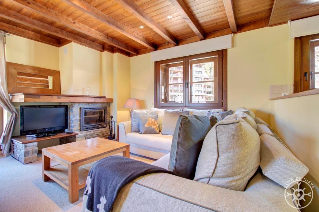 a living room with a couch and a tv at PEULHA de Alma de Nieve in Baqueira-Beret