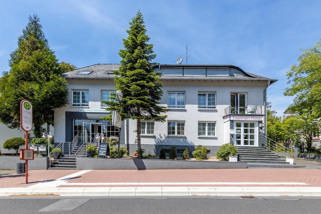 ein weißes Gebäude mit einem Baum davor in der Unterkunft Thermen Hotel & Restaurant Bad Soden in Bad Soden am Taunus