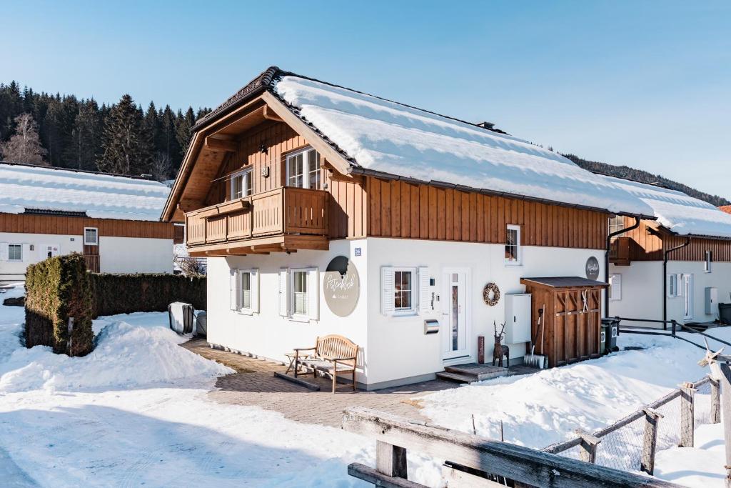 a house with a wooden roof in the snow at Pistenblick Chalet in Sankt Margarethen im Lungau