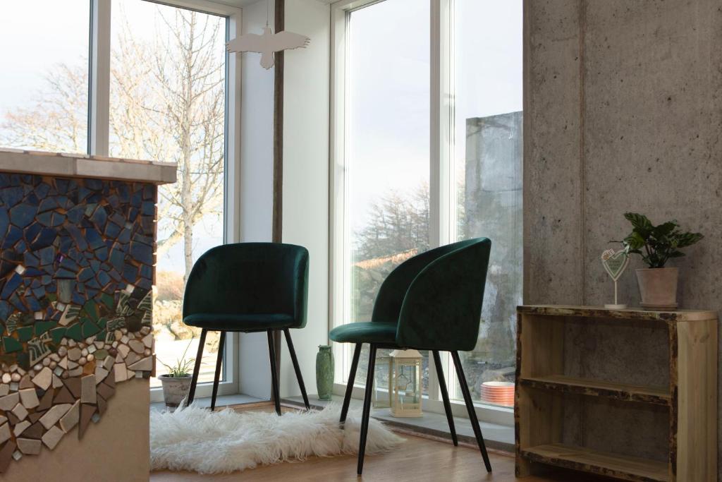 - deux chaises vertes dans une pièce avec cheminée dans l'établissement Úti í Kina, à Tórshavn