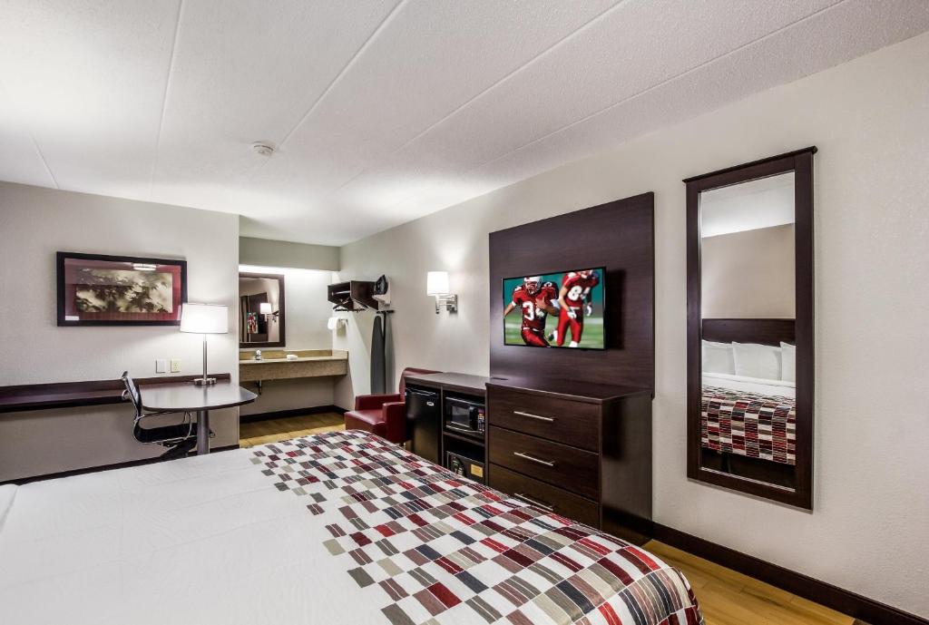 a hotel room with a bed and a desk and a mirror at Red Roof Inn Lexington in Lexington