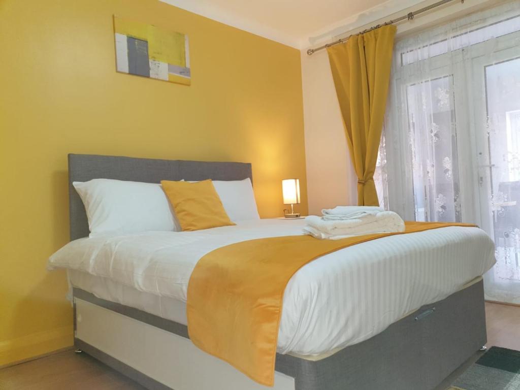 - une chambre avec un grand lit aux murs jaunes et une fenêtre dans l'établissement Large 4bed house up to 7beds parking Slough Train Station, à Slough