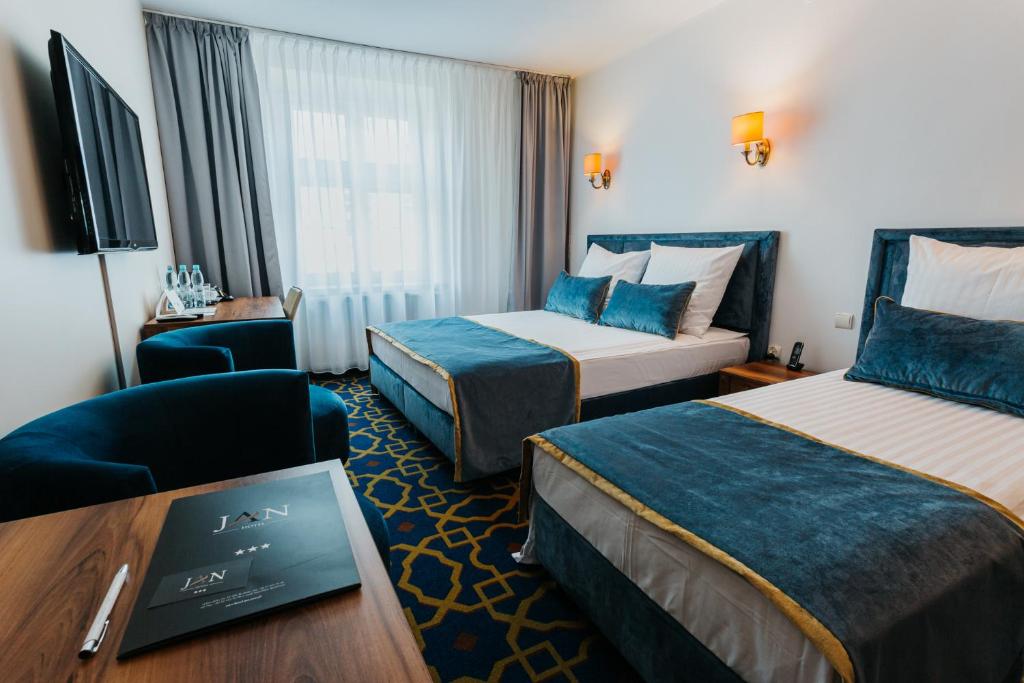 een hotelkamer met 2 bedden, een stoel en een tafel bij Hotel Jan in Krakau