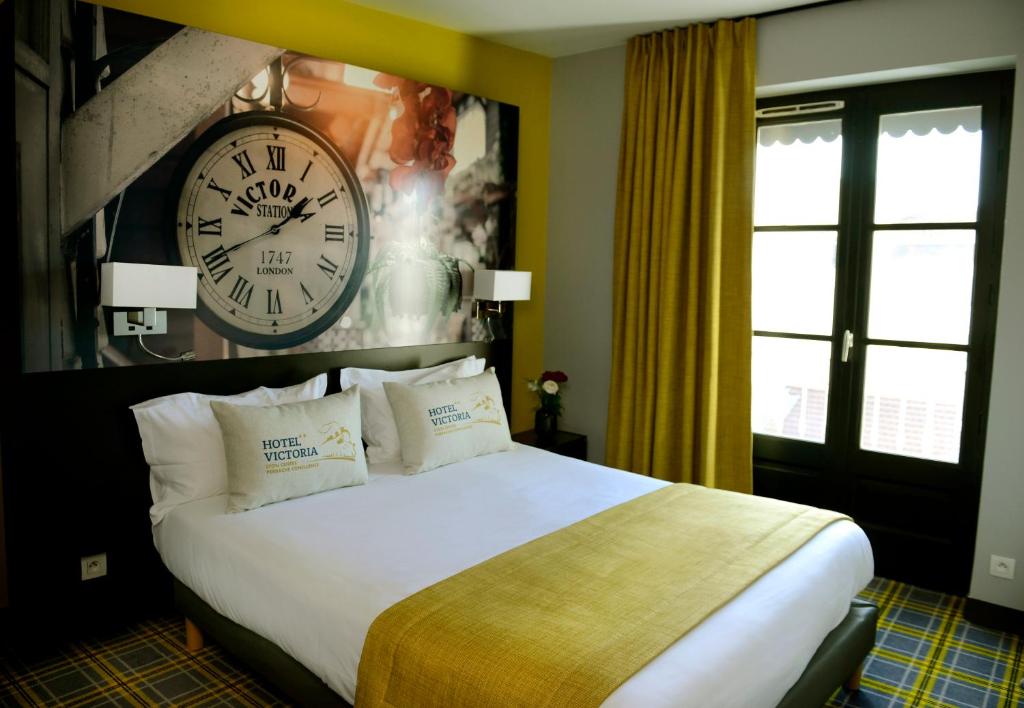 a bedroom with a large bed with a clock on the wall at Hotel Victoria Lyon Perrache Confluence in Lyon