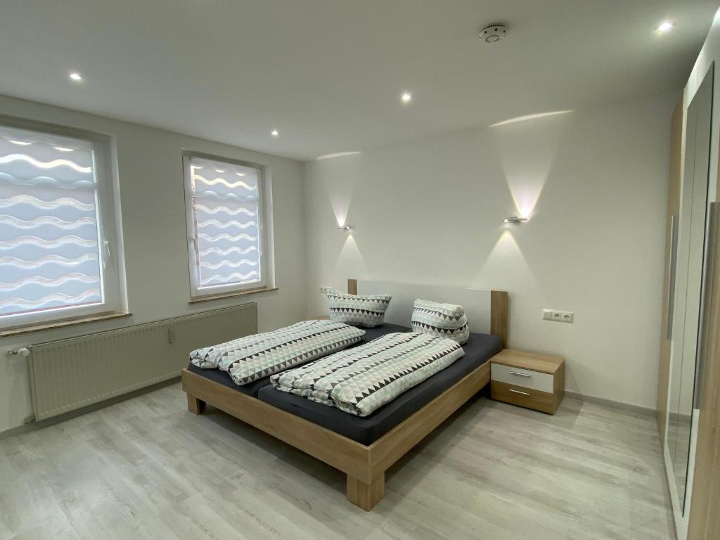 een slaapkamer met een bed en 2 ramen bij Ferienwohnung H&M Immobilien Hettstedt in Hettstedt