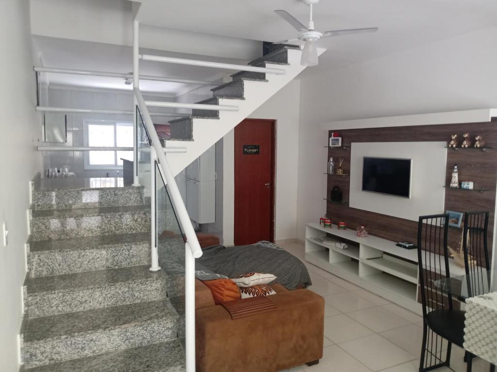 a living room with a staircase and a couch at Lindo sobrado a 100 m praia do Aruan. in Caraguatatuba