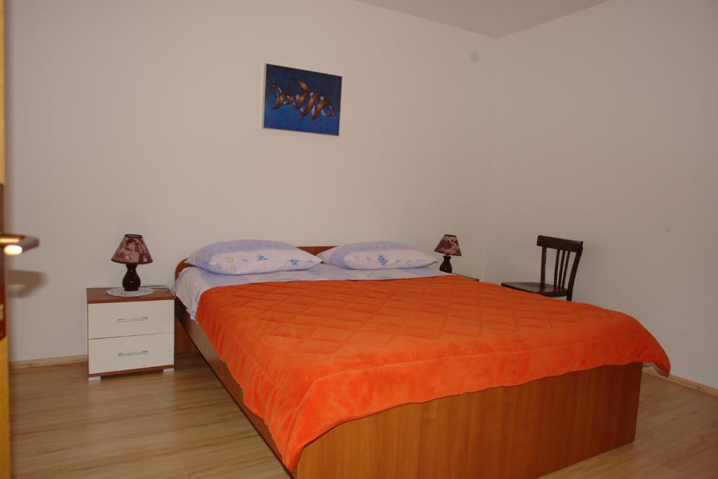 a bedroom with a bed with an orange blanket at Apartments Josipa in Mandre