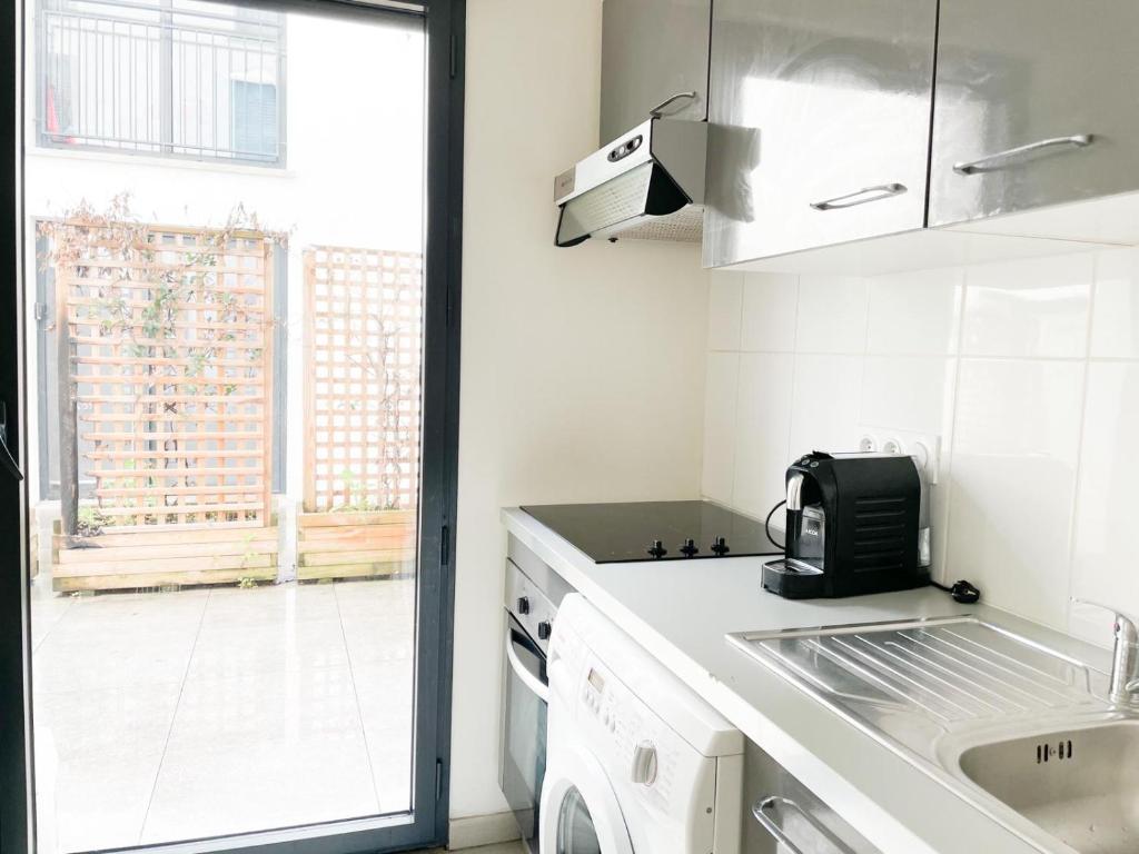 a white kitchen with a sink and a window at 003 - Appartement Moderne et Terrasse - Jeanne d&#39;Arc, Toulouse in Toulouse