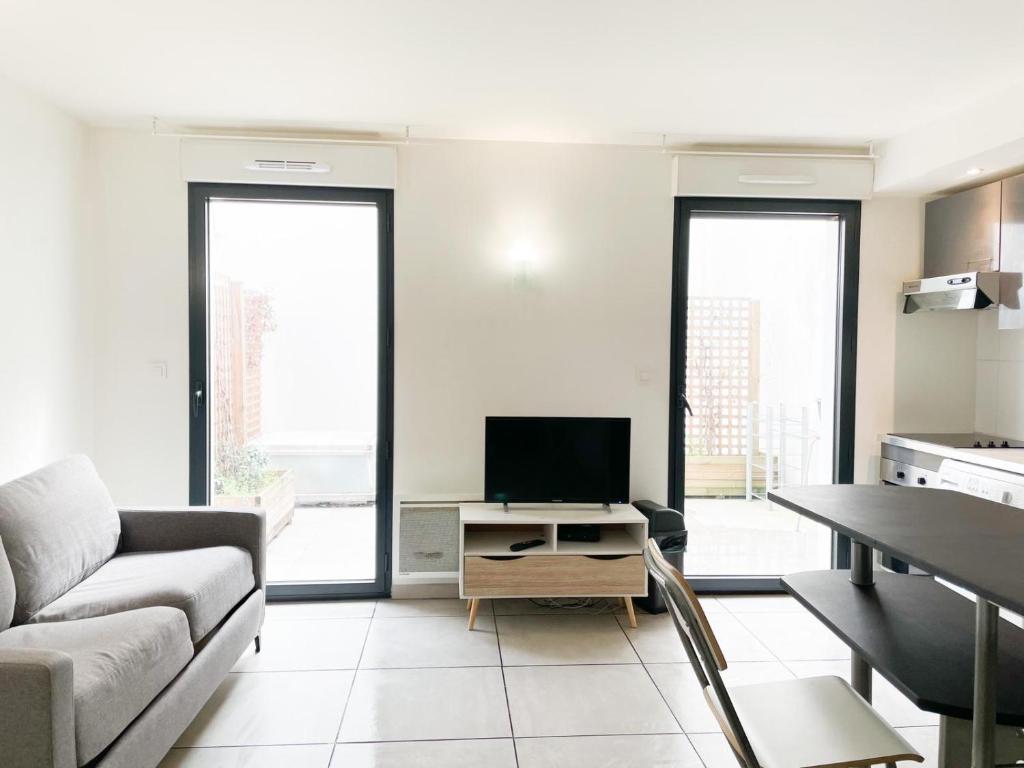 a living room with a couch and a tv at 003 - Appartement Moderne et Terrasse - Jeanne d&#39;Arc, Toulouse in Toulouse