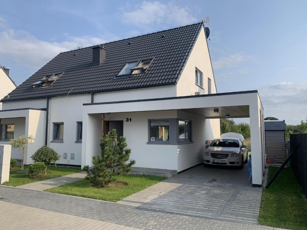 a white house with a car parked in a garage at Aquarella in Trzęsacz