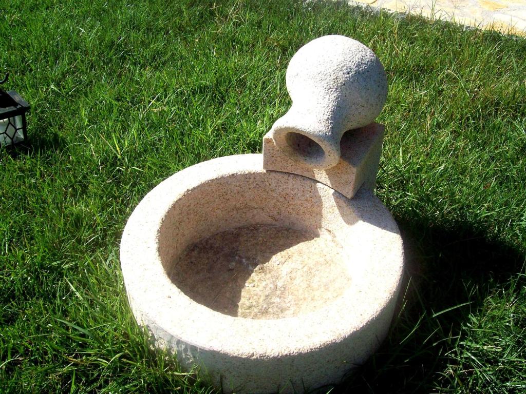 a statue of a toilet sitting in the grass at Minas Apartments in Divarata