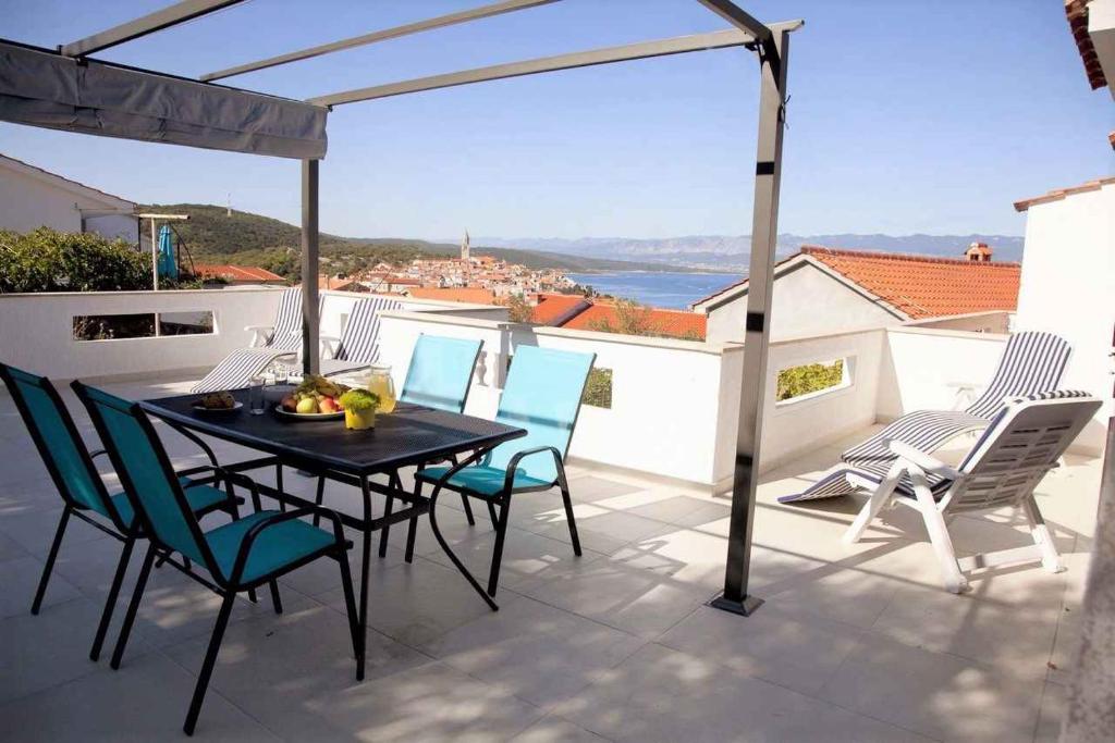 eine Terrasse mit einem Tisch und Stühlen auf dem Balkon in der Unterkunft Apartment in Vrbnik - Insel Krk 36848 in Vrbnik