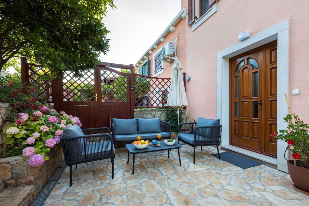 patio con sedie e tavolo di fronte a un edificio di Holiday home in Veli Losinj 40979 a Veli Lošinj (Lussingrande)