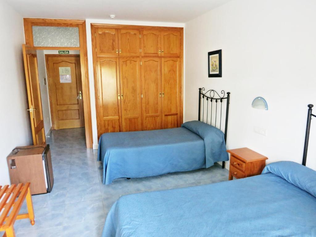 a bedroom with two beds and a wooden closet at Hostal Brisamar in San José
