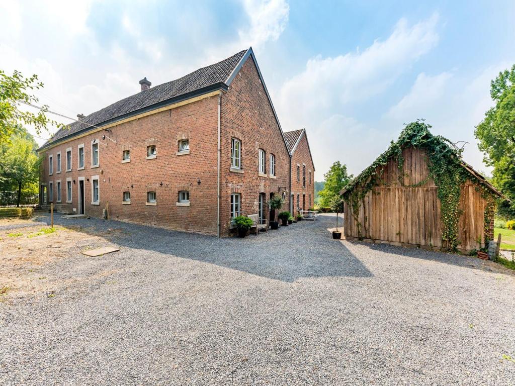- un grand bâtiment en briques avec une grange à côté dans l'établissement Magnificent Holiday Home in Sint Martens Voeren with Garden, à Berg