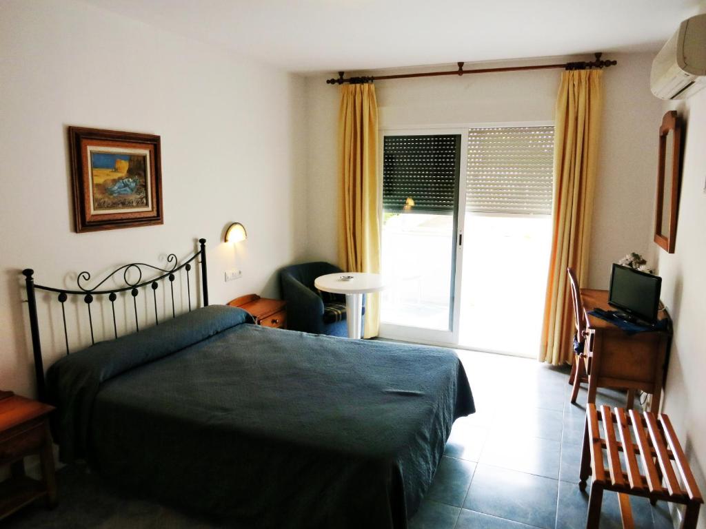 a bedroom with a bed with a green bedspread and a window at Hostal Brisamar in San José