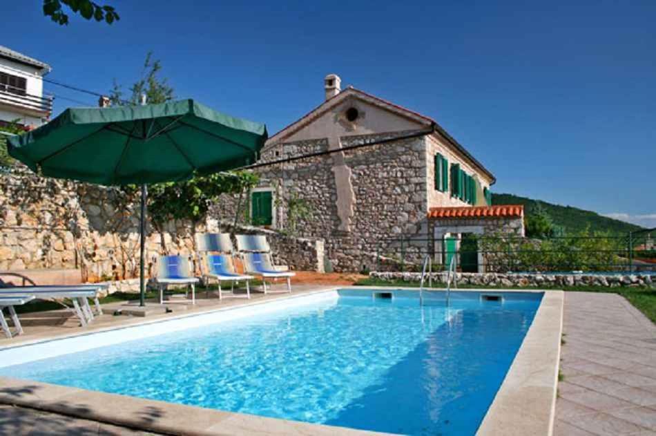 a house with a swimming pool and an umbrella at Holiday home in Crikvenica 39416 in Crikvenica