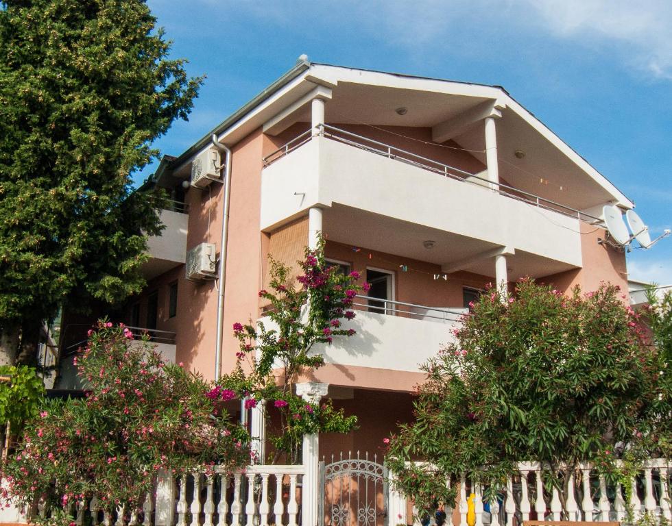 ein rosafarbenes Haus mit einem weißen Zaun in der Unterkunft Apartments Milka in Dobra Voda