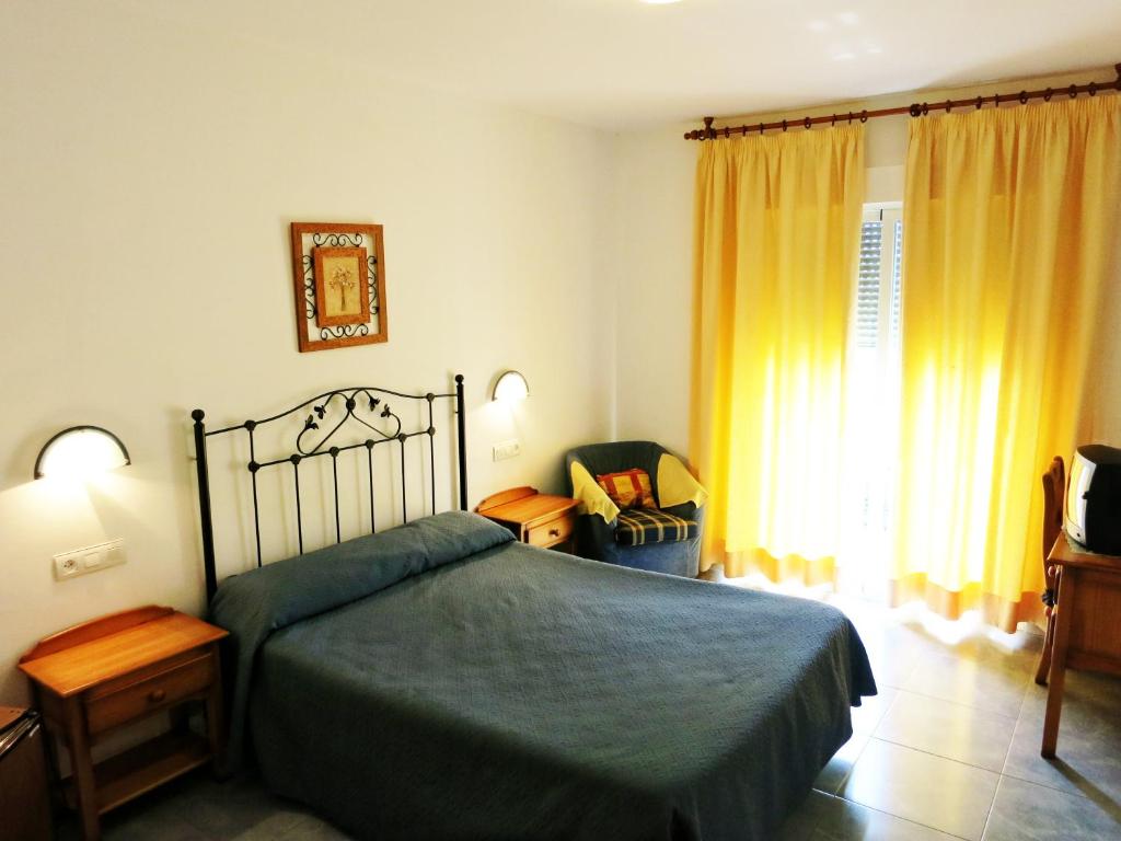 a bedroom with a bed and a chair and a window at Hostal Brisamar in San José