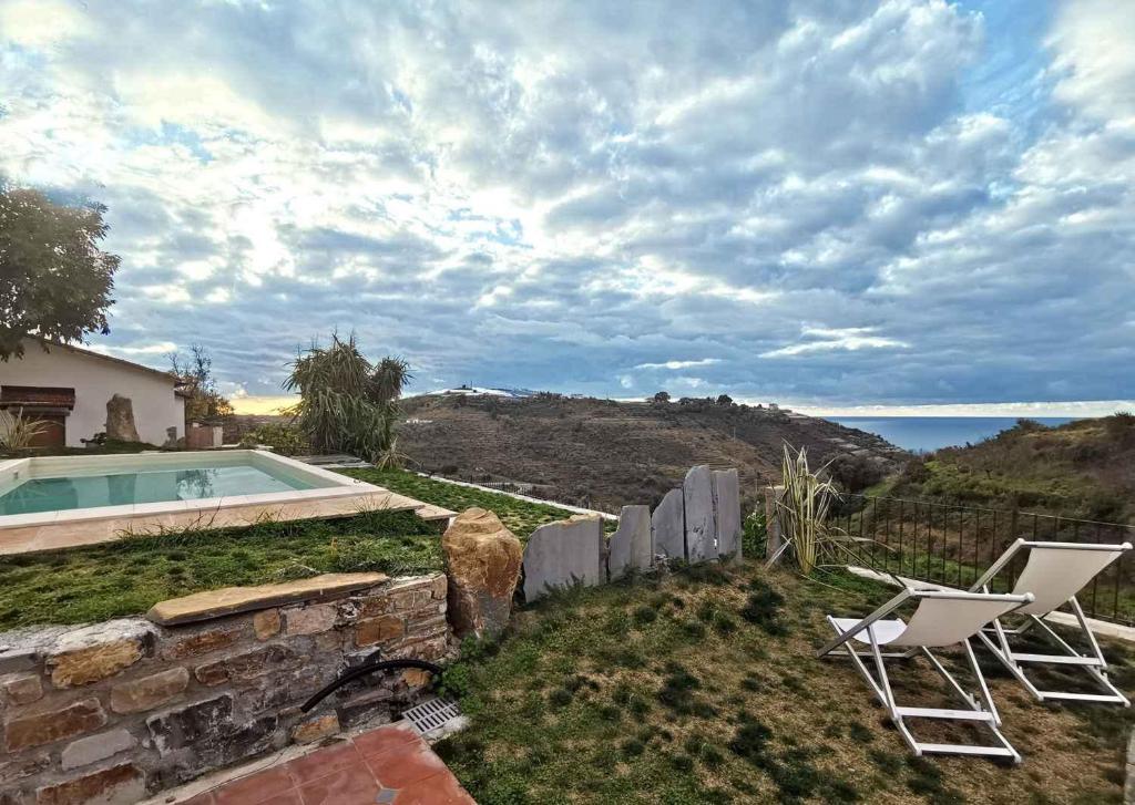 ein Haus mit einem Pool und zwei Stühlen in der Unterkunft Holiday home in Pompeiana 40835 in Pompeiana