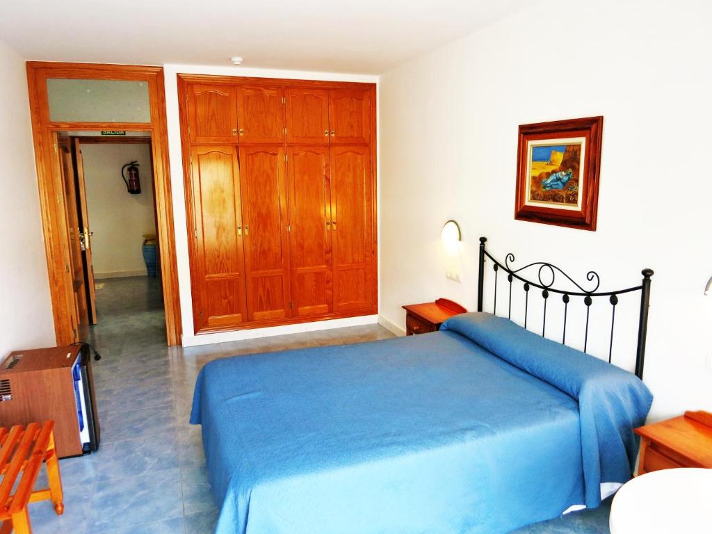a bedroom with a blue bed and a wooden cabinet at Hostal Brisamar in San José