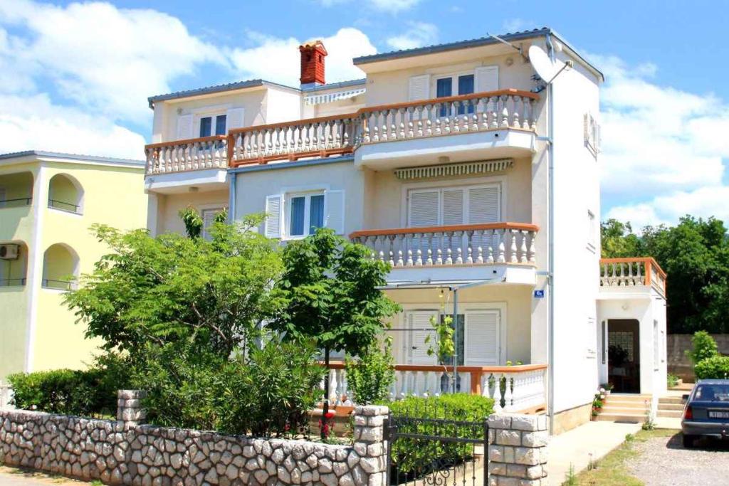 ein weißes Haus mit einem Zaun davor in der Unterkunft Apartments in Jadranovo 39275 in Jadranovo