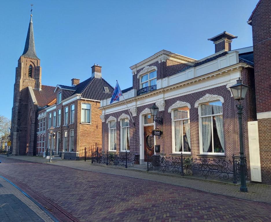 uma rua de calçada com edifícios e uma igreja em hotel 't Doktershus em Lemmer