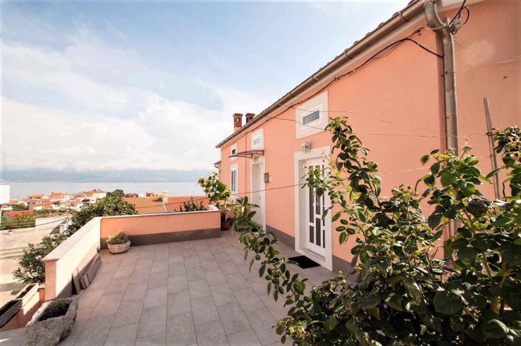 a pink building with a balcony with a view of the ocean at Studio in Vrbnik/Insel Krk 36786 in Vrbnik