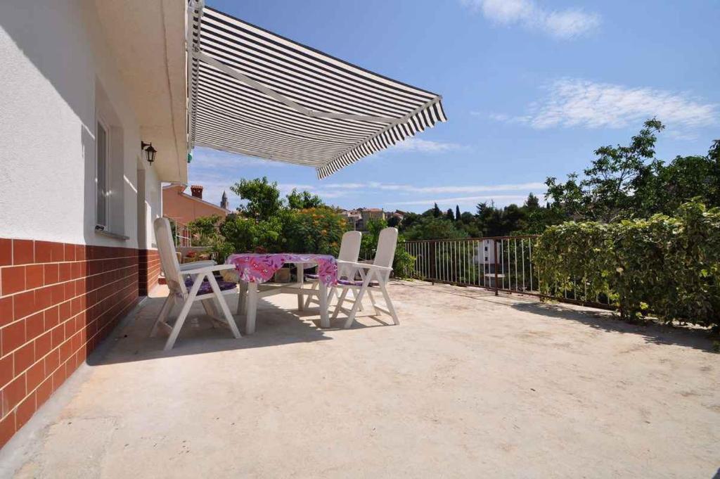 a table and chairs on a patio with a canopy at Apartment in Vrbnik/Insel Krk 36796 in Vrbnik