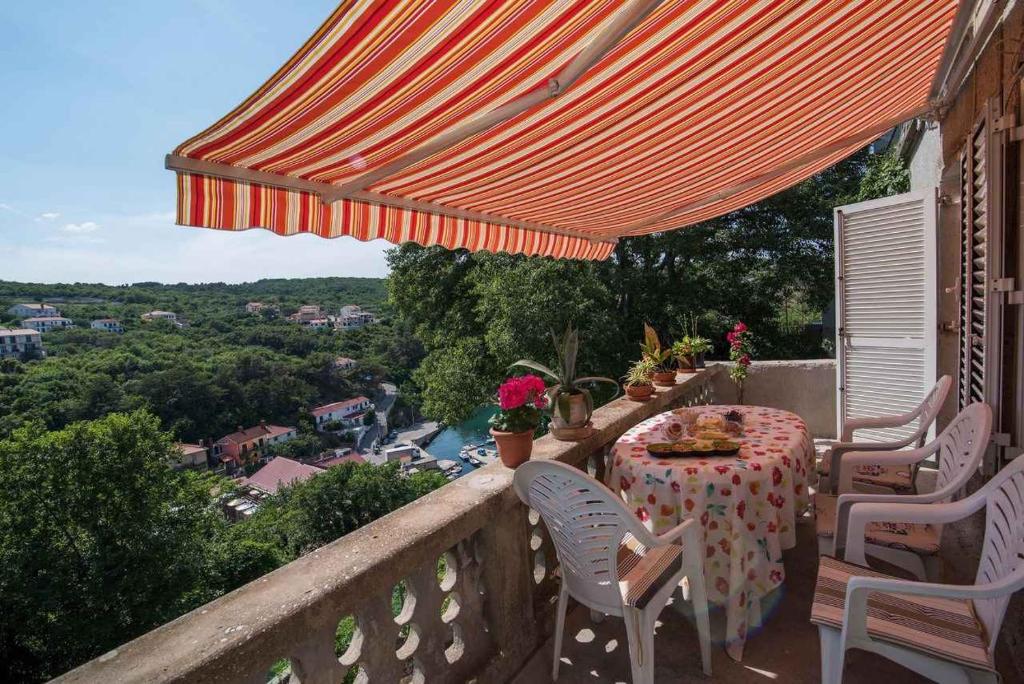 a table and chairs on a balcony with an orange umbrella at Holiday home in Vrbnik/Insel Krk 36717 in Vrbnik