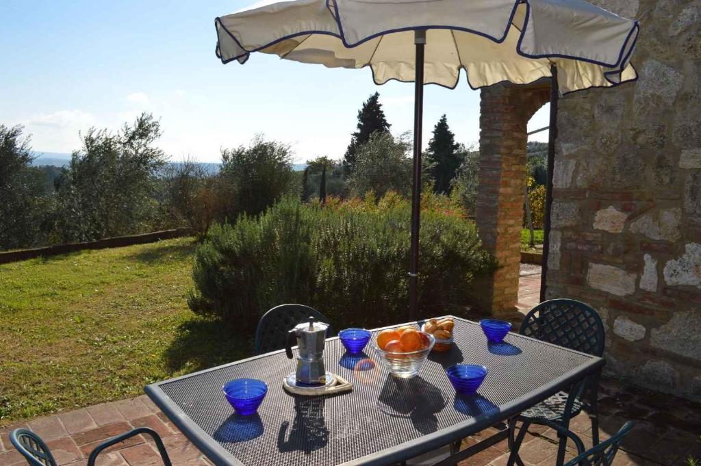 a table with blue glasses on it with an umbrella at Apartment in Asciano/Toskana 24106 in Asciano