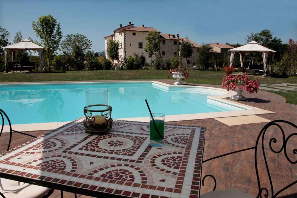 un tavolo con un drink accanto alla piscina di Apartment in Capolona/Toskana 23622 a Capolona