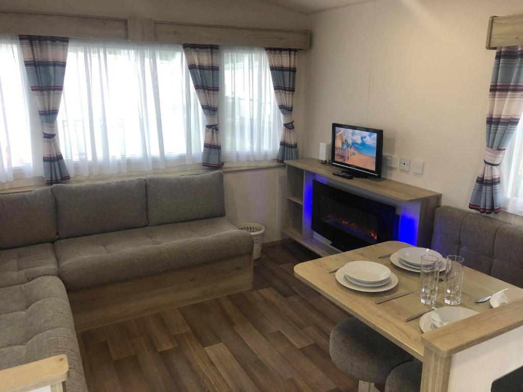 a living room with a couch and a table at Ash Standard Holiday Home in Chapel Saint Leonards