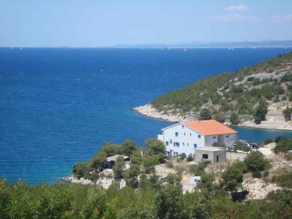 a white house on a hill next to the water at Apartments in Hvar/Insel Hvar 33535 in Hvar