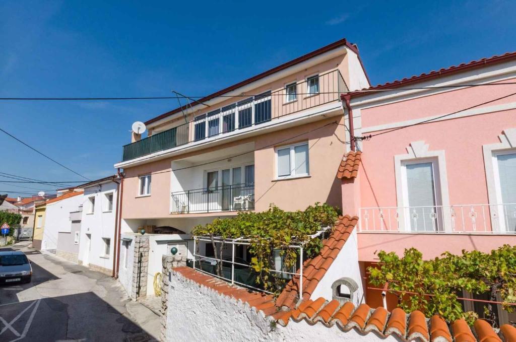 a pink and white house with a fence at Apartments in Novi Vinodolski 15234 in Novi Vinodolski