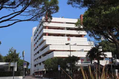 un grande edificio bianco con alberi di fronte di Apartments in Lignano Sabbiadoro 21784 a Lignano Sabbiadoro