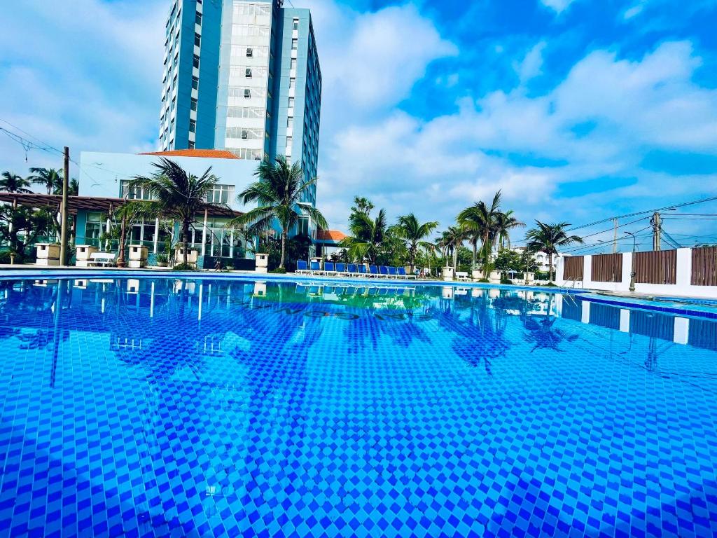 a large blue swimming pool in front of a tall building at Sai Gon Phu Yen Hotel in Tuy Hoa