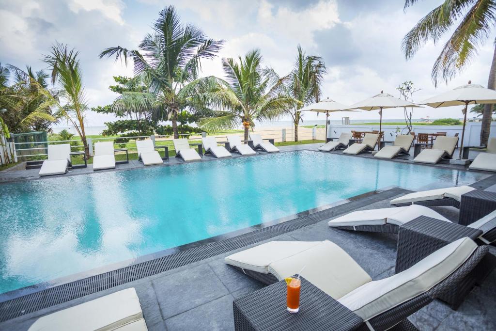 a swimming pool with lounge chairs and umbrellas at The Beach Apartments in Negombo