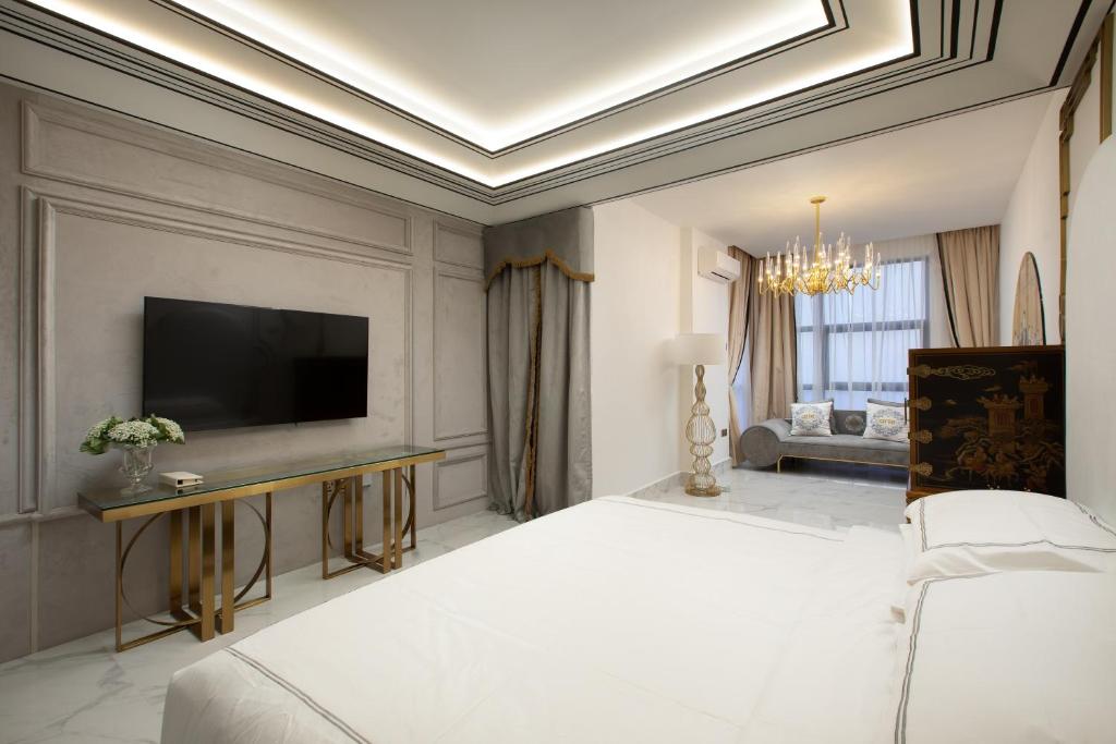 A large bedroom view showing the bed, television wall and an adjoining decorated sitting area.