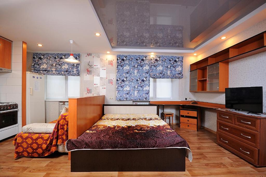 オムスクにあるOmsk Sutki Apartments on Irtyshskaya Naberezhnaya 13のベッドルーム1室(ベッド1台付)、キッチン(青いカーテン付)