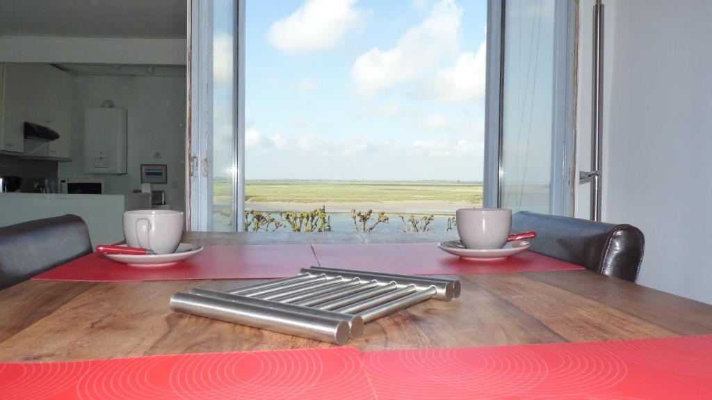 a table with a red table cloth and two cups on it at Violette avec parking privé sécurisé in Saint-Valery-sur-Somme