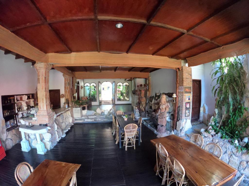 una sala de estar abierta con mesas y sillas de madera. en PIAS POPPIES HOTEL, en Rantepao