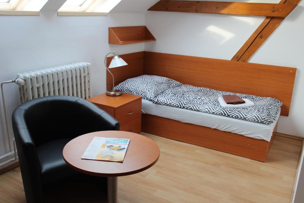 a bedroom with a bed and a chair and a table at Ubytování Na špejcharu, Želevčice in Slaný