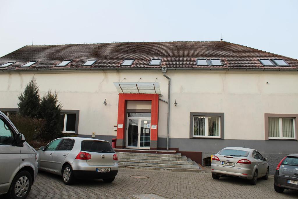 two cars parked in front of a building with a red door at Ubytování Na špejcharu, Želevčice in Slaný