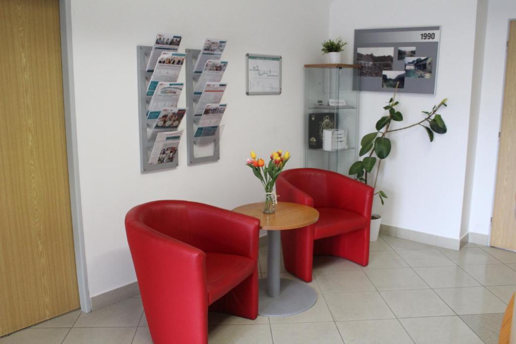 a table and two red chairs in a waiting room at Ubytování Na špejcharu, Želevčice in Slaný