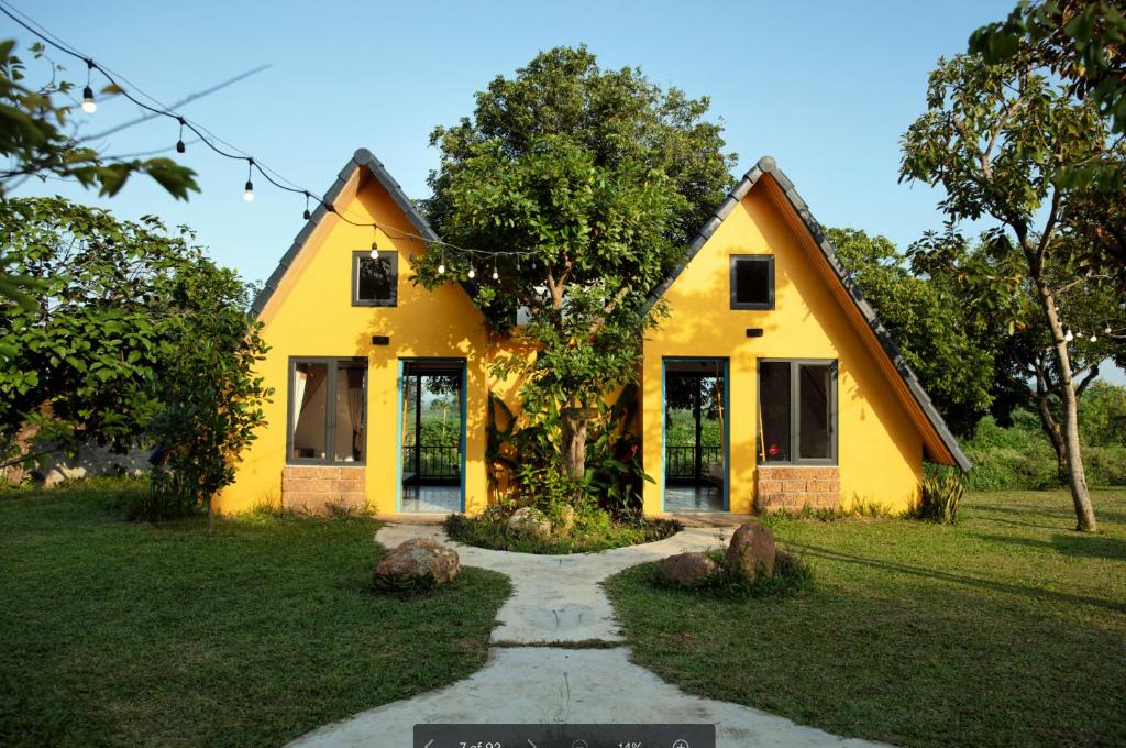 una casa gialla con un sentiero di fronte di Bavi Annam Garden a Ba Vì