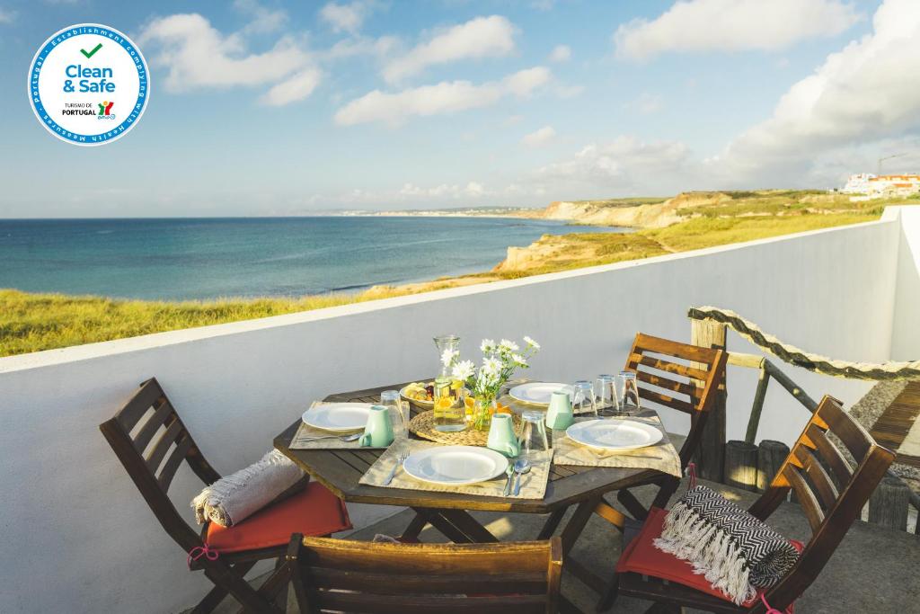 a table and chairs on a balcony with a view of the ocean at SoulSurfcamp Portugal in Peniche